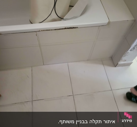 אמבטיה עם סימני רטיבות על הקיר והרצפה